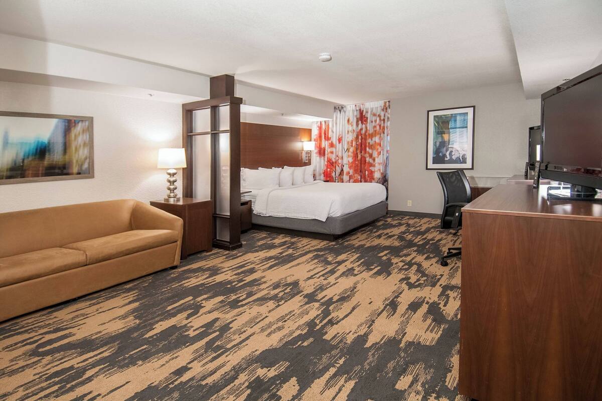 Habitación de hotel con cama, sofá, escritorio y televisión.