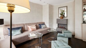 A modern living room with a sofa, two glass tables, and a fireplace.