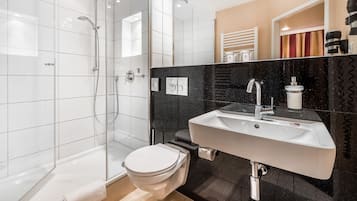 Ein modernes Badezimmer mit einer Duschkabine, einer weißen Toilette und einem Waschbecken mit schwarzer Arbeitsplatte.