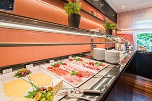 A buffet with various food options including hard cheese, meats, and vegetables. - Best Western Raphael Hotel Altona (Hamburg)