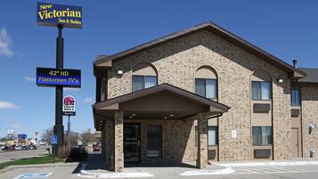 A hotel with a brick facade, a flat entrance, and signs for a 42" HD flatscreen TV, a Taco Bell drive-thru, and a New Victorian Inn & Suites.