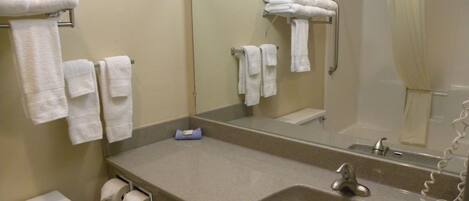 A bathroom with a sink, mirror, and multiple towels on towel racks.