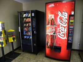 Zona de máquinas expendedoras, con una máquina de Coca-Cola y diversas opciones de aperitivos y bebidas.