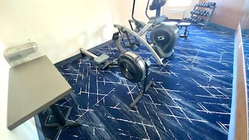 Een sportschool met trainingsapparatuur, een projectiescherm en kunstwerken aan de muren.