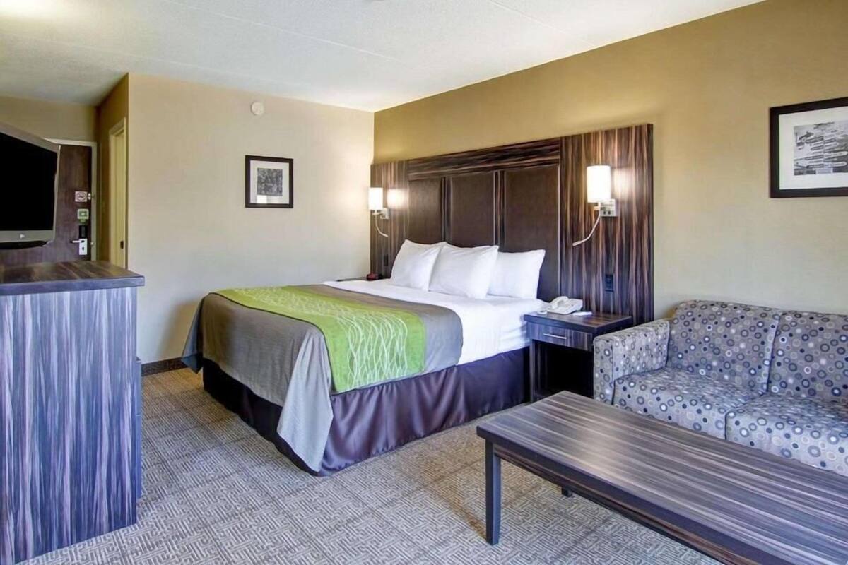 Una habitación de hotel con cama, escritorio, silla y televisor.