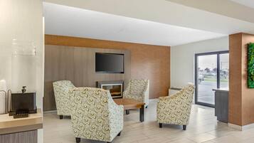 Un vestíbulo moderno con sillones estampados, un televisor de pantalla plana y una recepción.