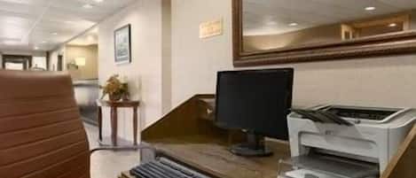 A modern office with a wooden desk, a computer monitor, and a printer.