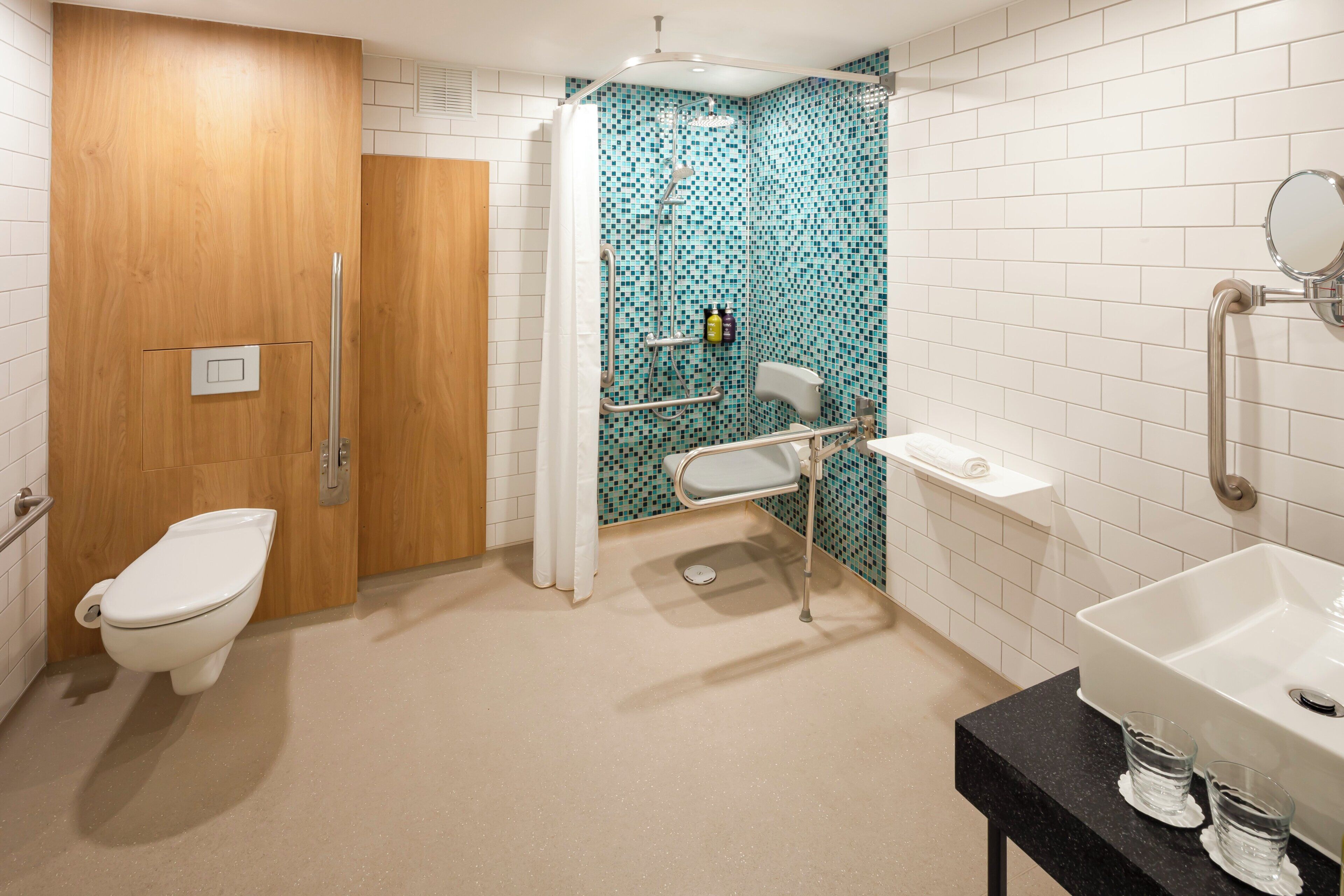 Et badeværelse med toilet, brusebad, vask og spejl.