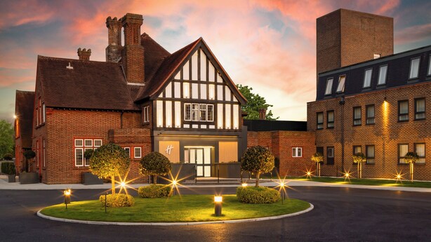 A Tudor-style building with a prominent entrance, a brick facade, and a well-maintained lawn with lighting. - Holiday Inn London-Bexley by IHG (Bexley)