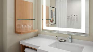 Un baño moderno con un espejo grande, lavamanos blanco y un armario de madera.