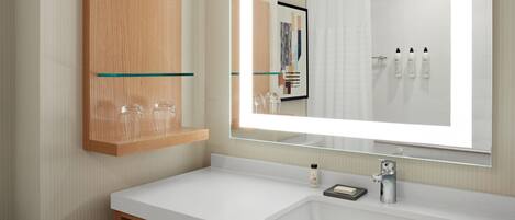 A modern bathroom with a large mirror, white sink, and wooden medicine cabinet.