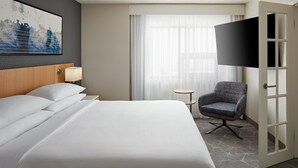 A hotel room with a large bed, a chair, a TV, and a door. - Delta Hotels by Marriott Calgary Airport In-Terminal (Calgary)