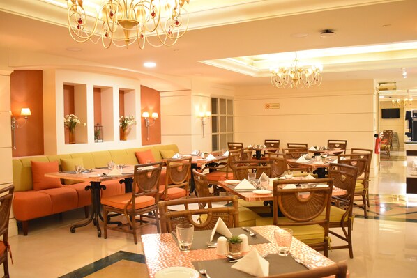 A dining area with multiple tables and chairs, a sofa, and decorative wall sconces.