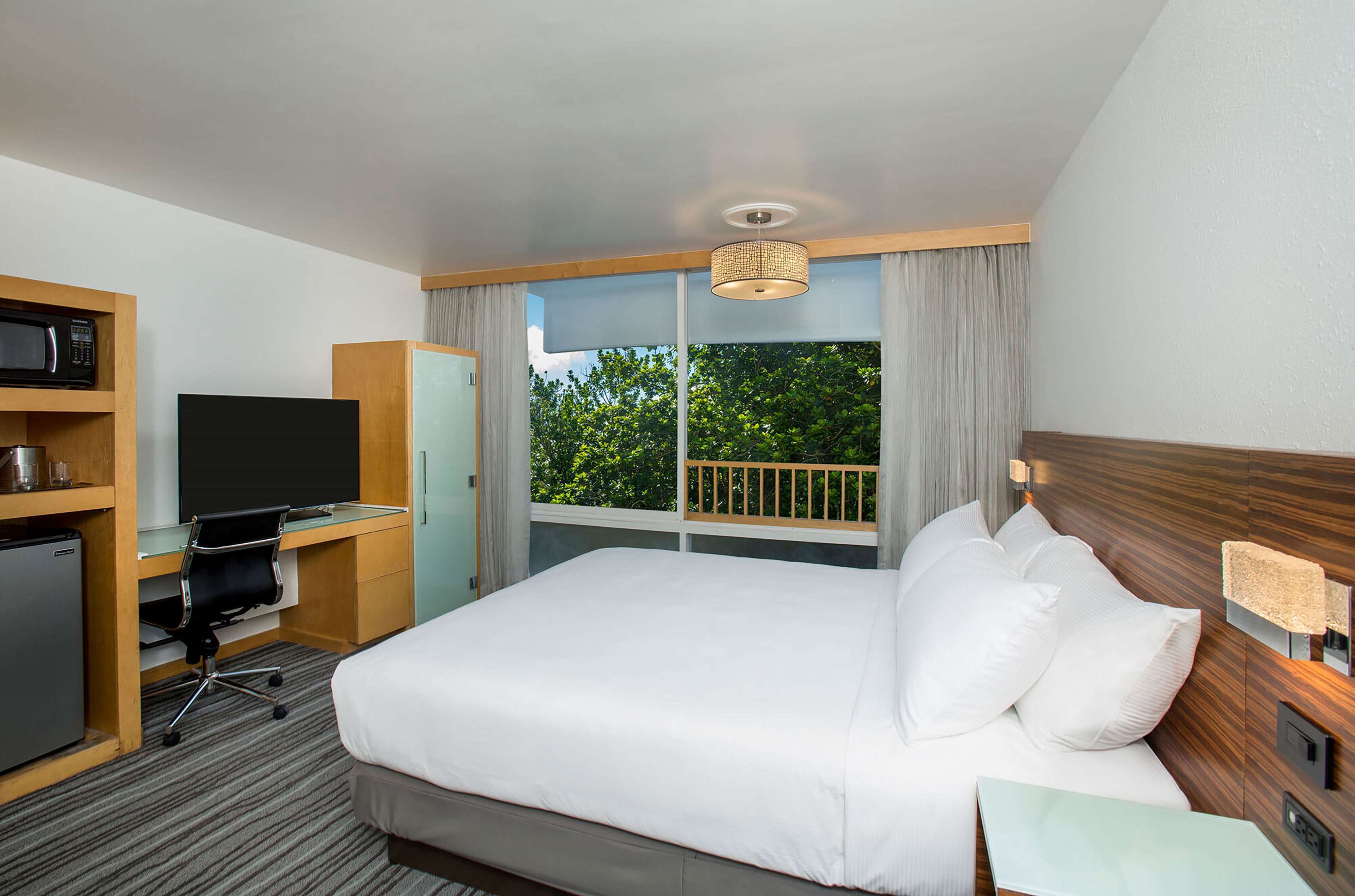 Une chambre d’hôtel équipée d’un lit, d’un bureau avec un ordinateur, d’une télévision et d’un mini-bar.