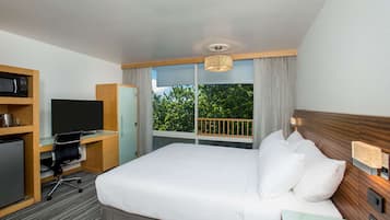 Une chambre d’hôtel équipée d’un lit, d’un bureau avec un ordinateur, d’une télévision et d’un mini-bar.
