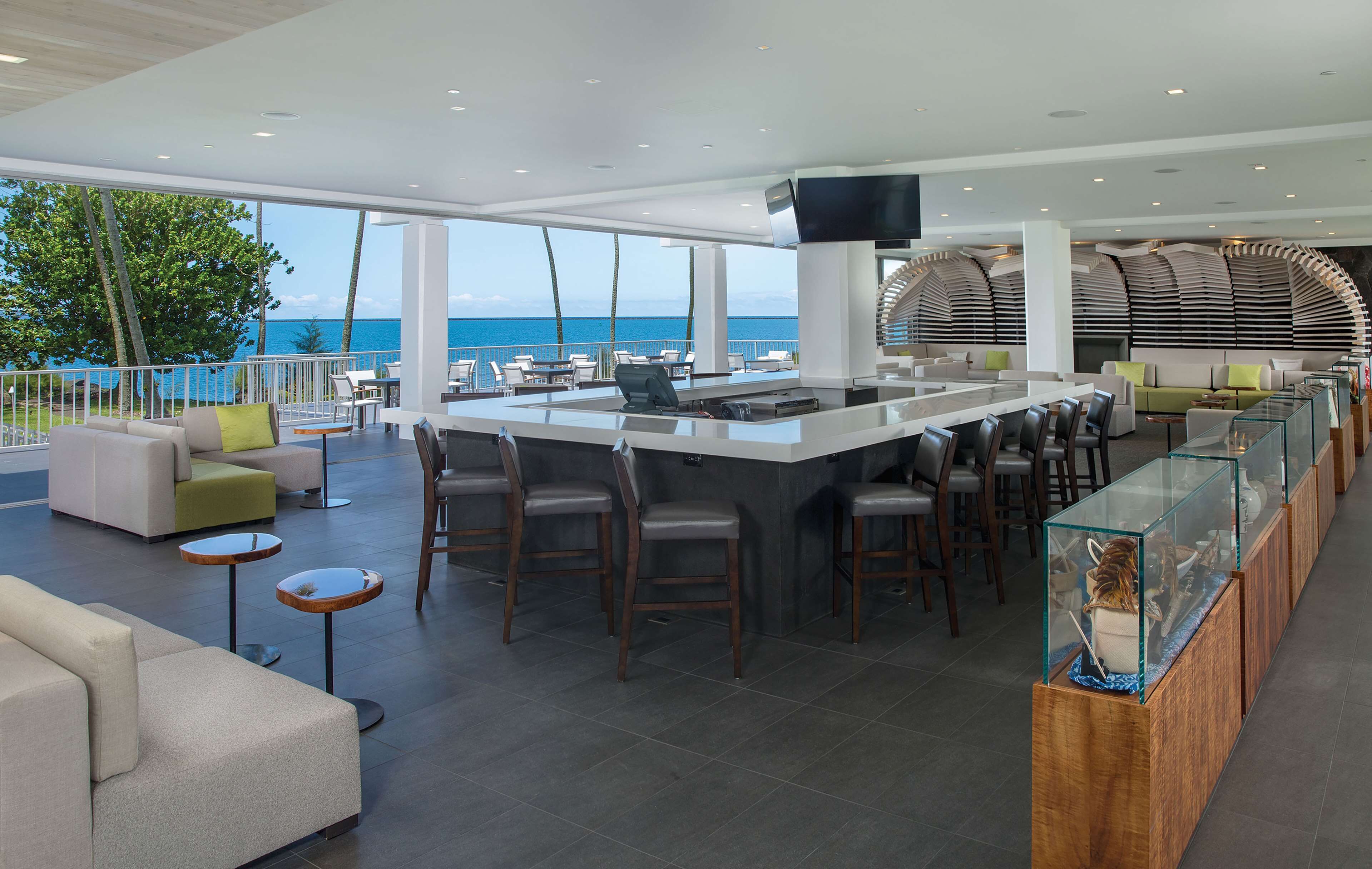 Zona de bar moderna con una barra larga, asientos y vista al mar.