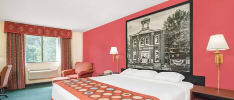 Una habitación de hotel con una cama grande, una silla, un escritorio, una lámpara y una ventana con cortinas.