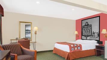 Een hotelkamer met een bed, een stoel, een bureau en een lamp.