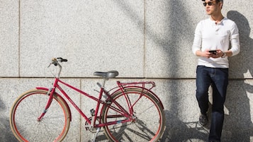 A red bicycle parked against a textured wall.