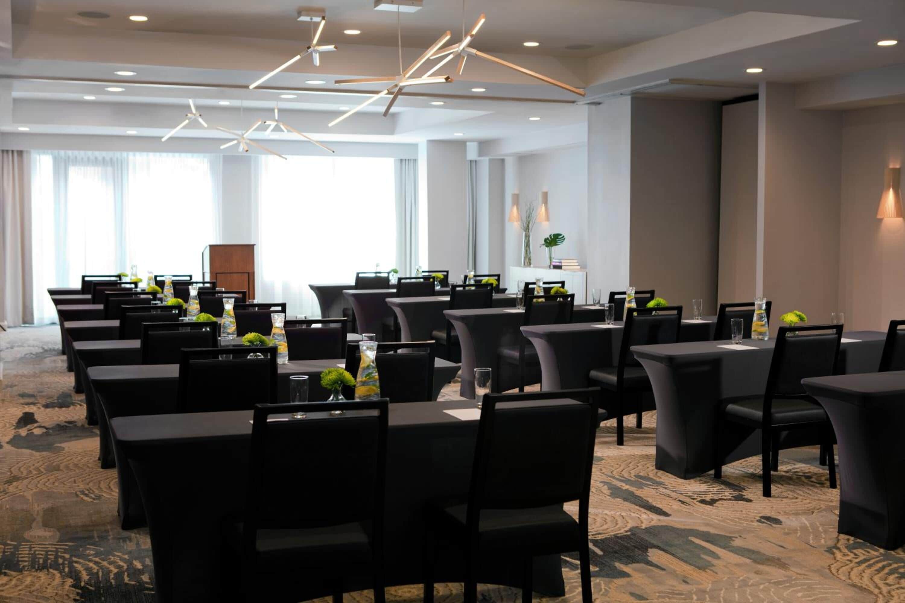 A conference room with multiple tables and chairs, arranged in rows.