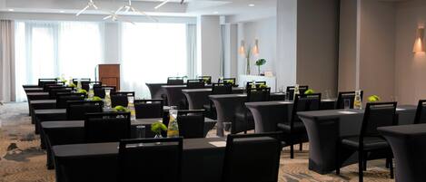 A conference room with multiple tables and chairs, arranged in rows.