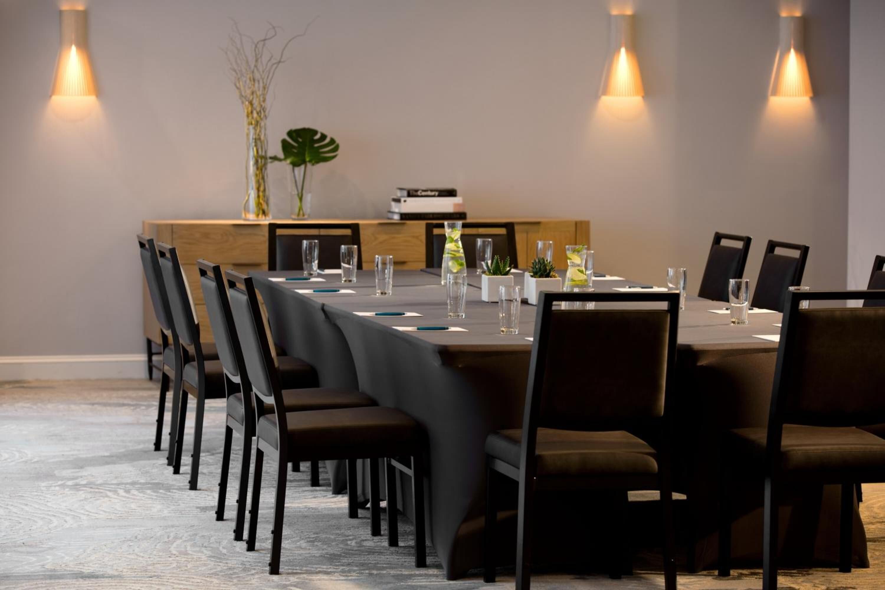 A conference room with a long table, chairs, and a small plant on the table.