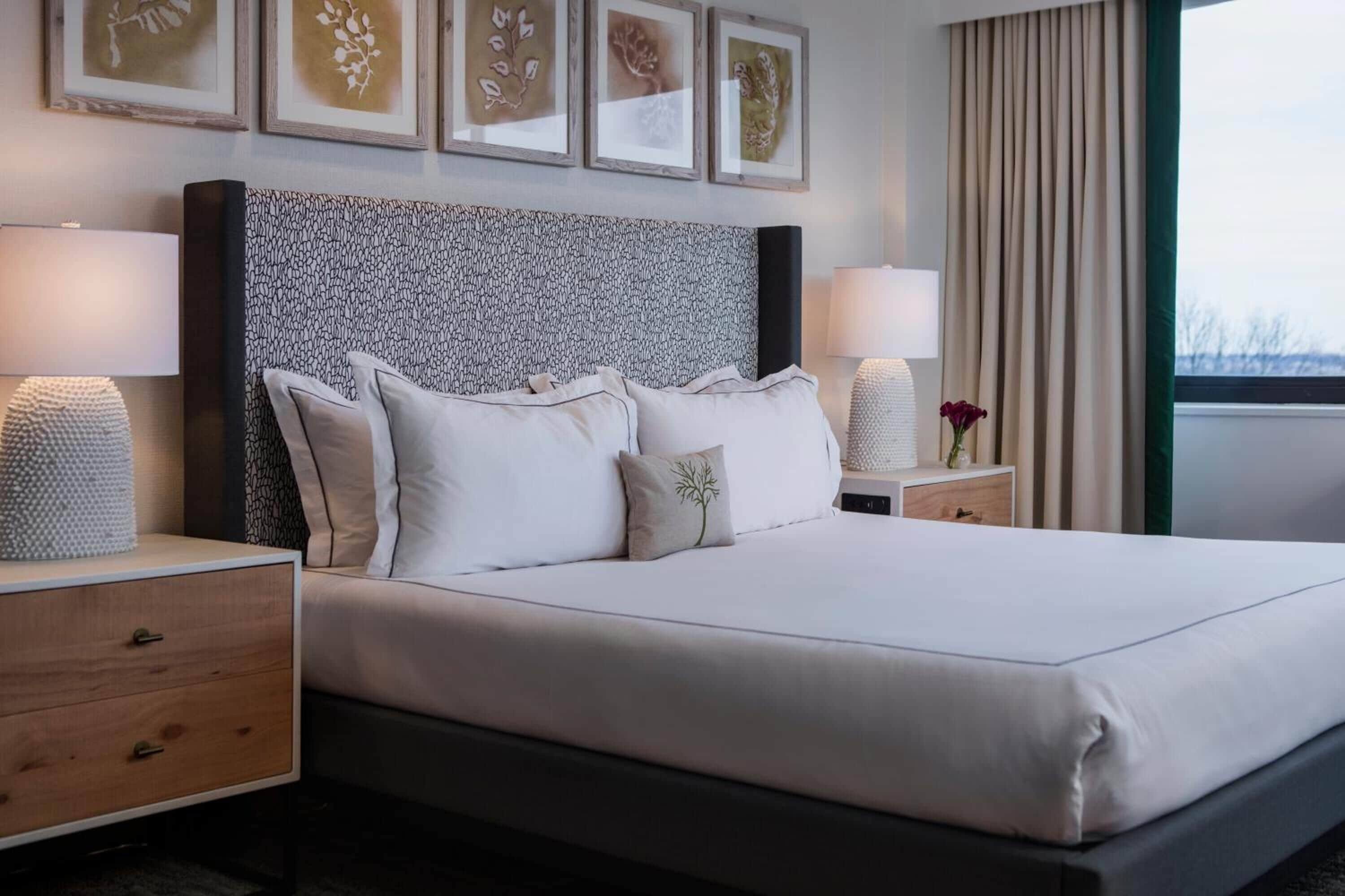 A neatly made bed with a patterned headboard, bedside tables with lamps, and framed artwork on the wall.