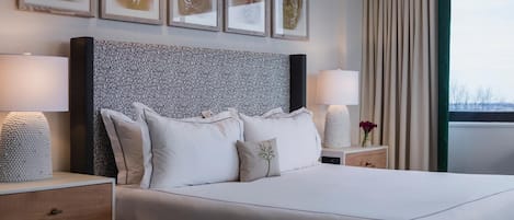 A neatly made bed with a patterned headboard, bedside tables with lamps, and framed artwork on the wall.