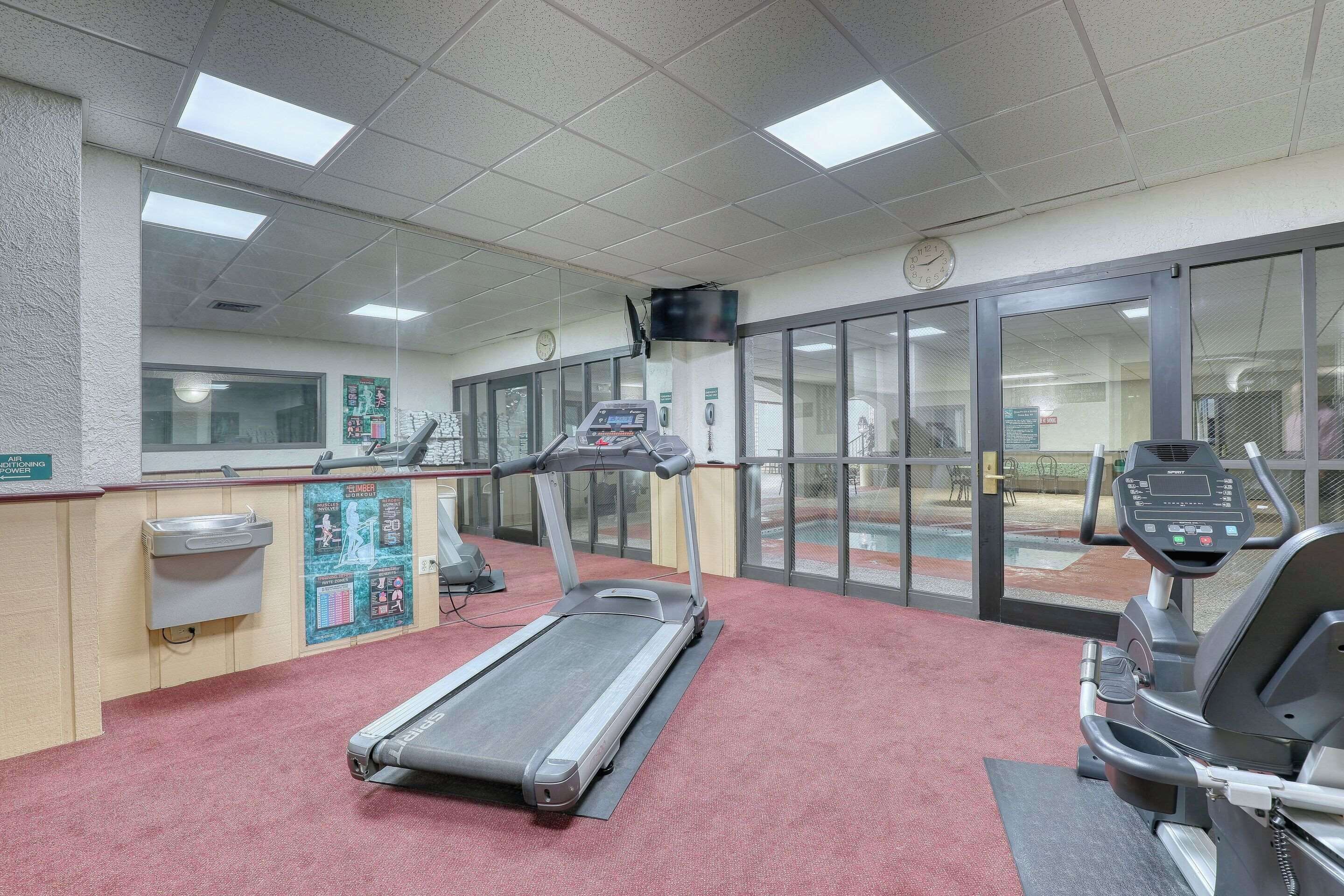 Une salle de sport équipée de tapis de course, d’un vélo d’appartement et d’un distributeur d’eau.