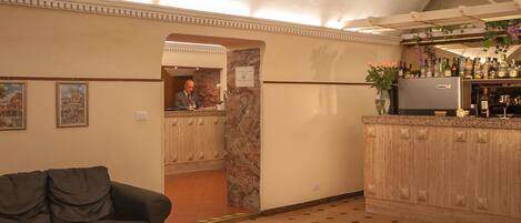 A hotel lobby with a bar area, a sofa, and a floral arrangement on a coffee table.