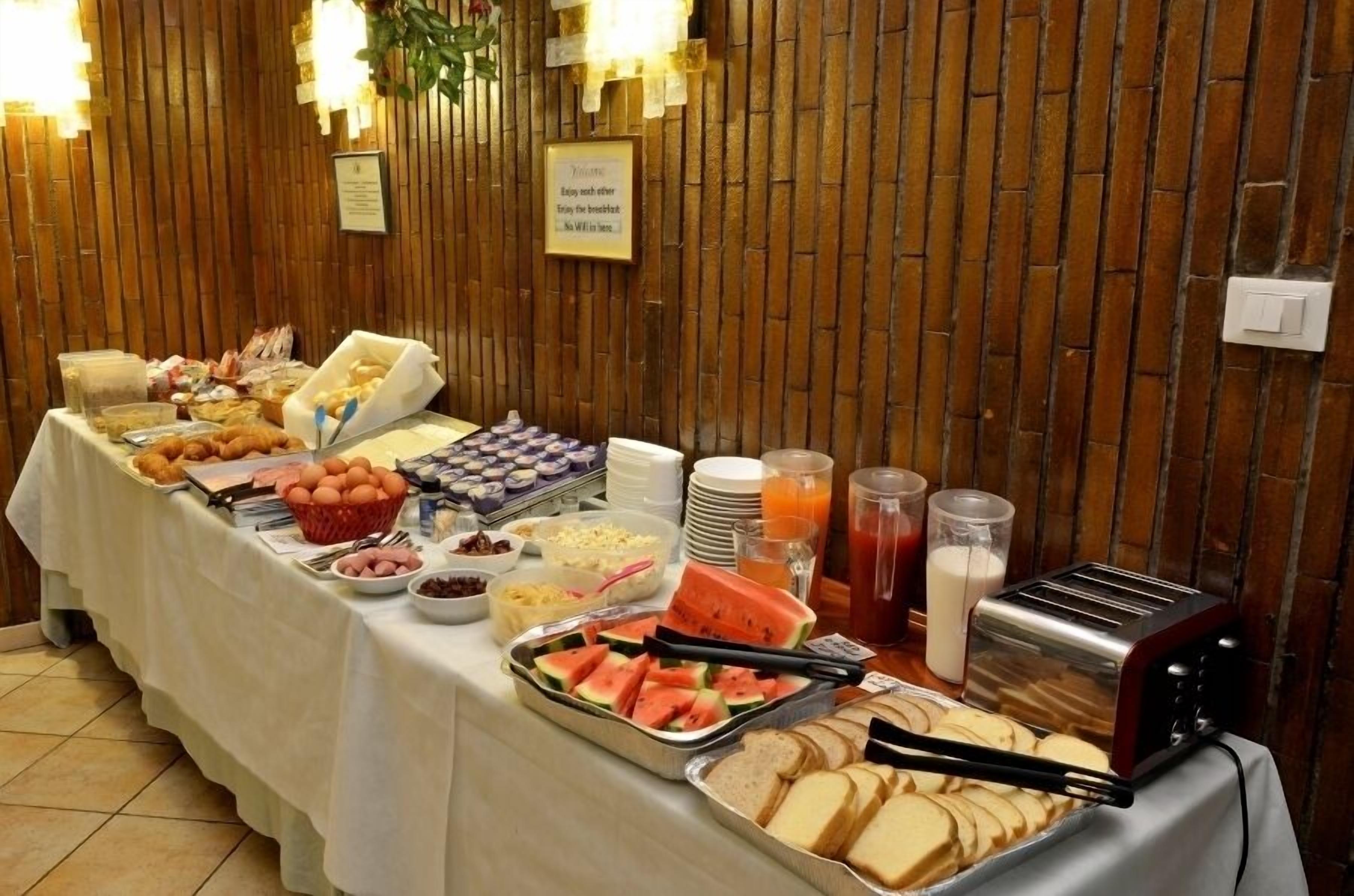 Una mesa de buffet con diversos alimentos para el desayuno, como pan, huevos y fruta.