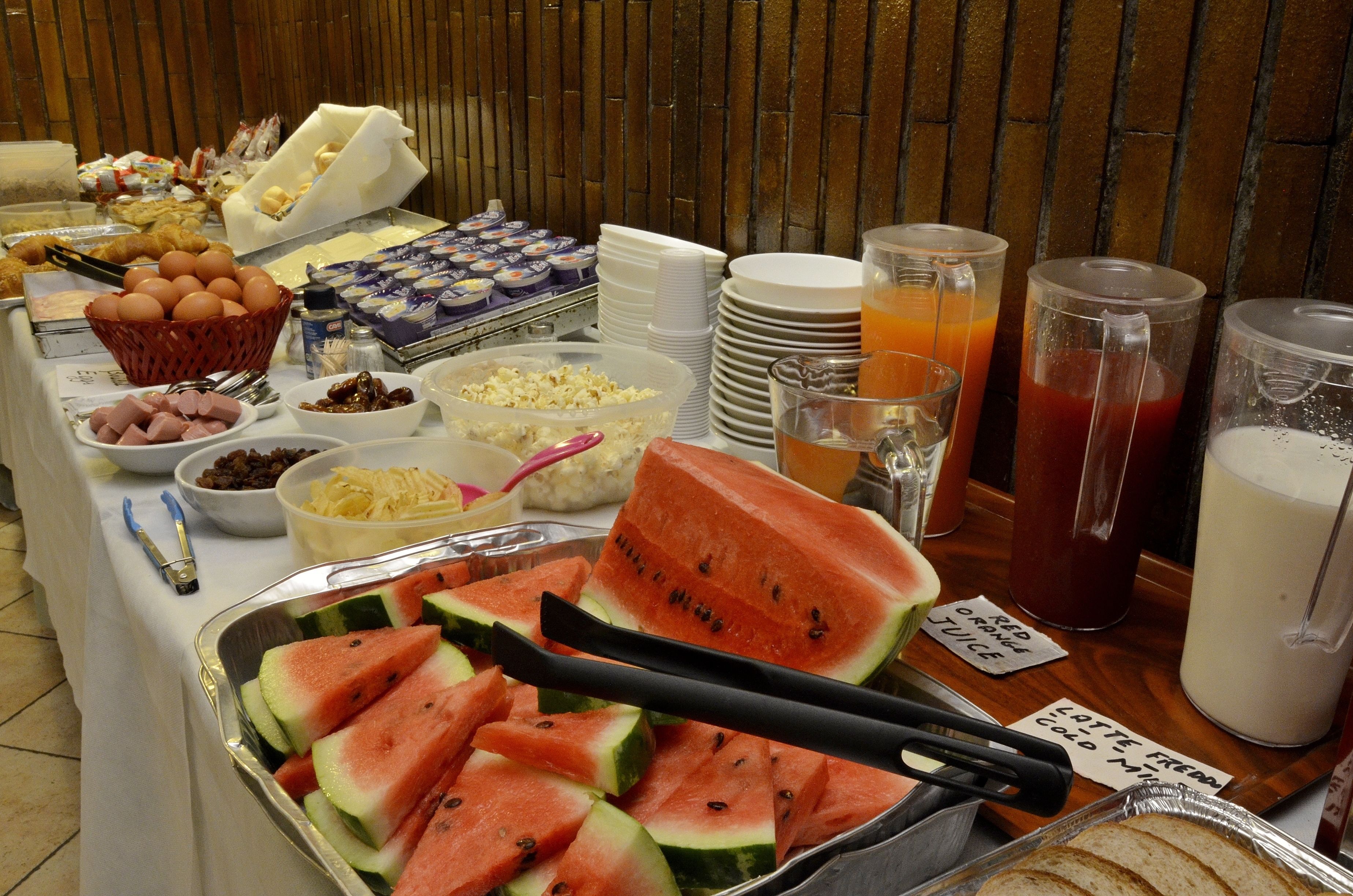 A buffet with various food items including watermelon slices, eggs, and beverages.