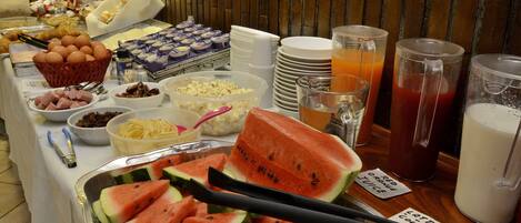 A buffet with various food items including watermelon slices, eggs, and beverages.