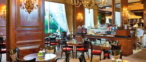 A hotel lobby with multiple seating areas, chandeliers, and a reception desk.