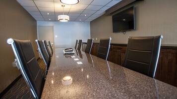 A conference room with a long table, chairs, a television, and a ceiling light.