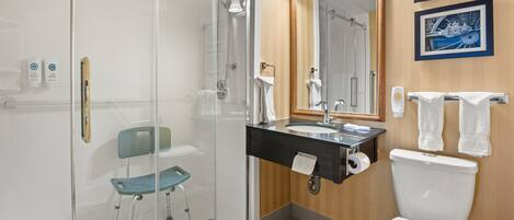 Ein modernes Badezimmer mit Duschkabine aus Glas, einem Waschbecken mit Spiegel darüber und einer Toilette.