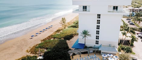 Un hôtel situé en bord de mer, doté d’une piscine, de chaises longues et offrant une vue sur l’océan.