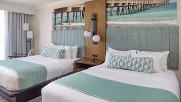 A hotel room with two beds, a large window with curtains, a painting of a pier, and a nightstand with a lamp.