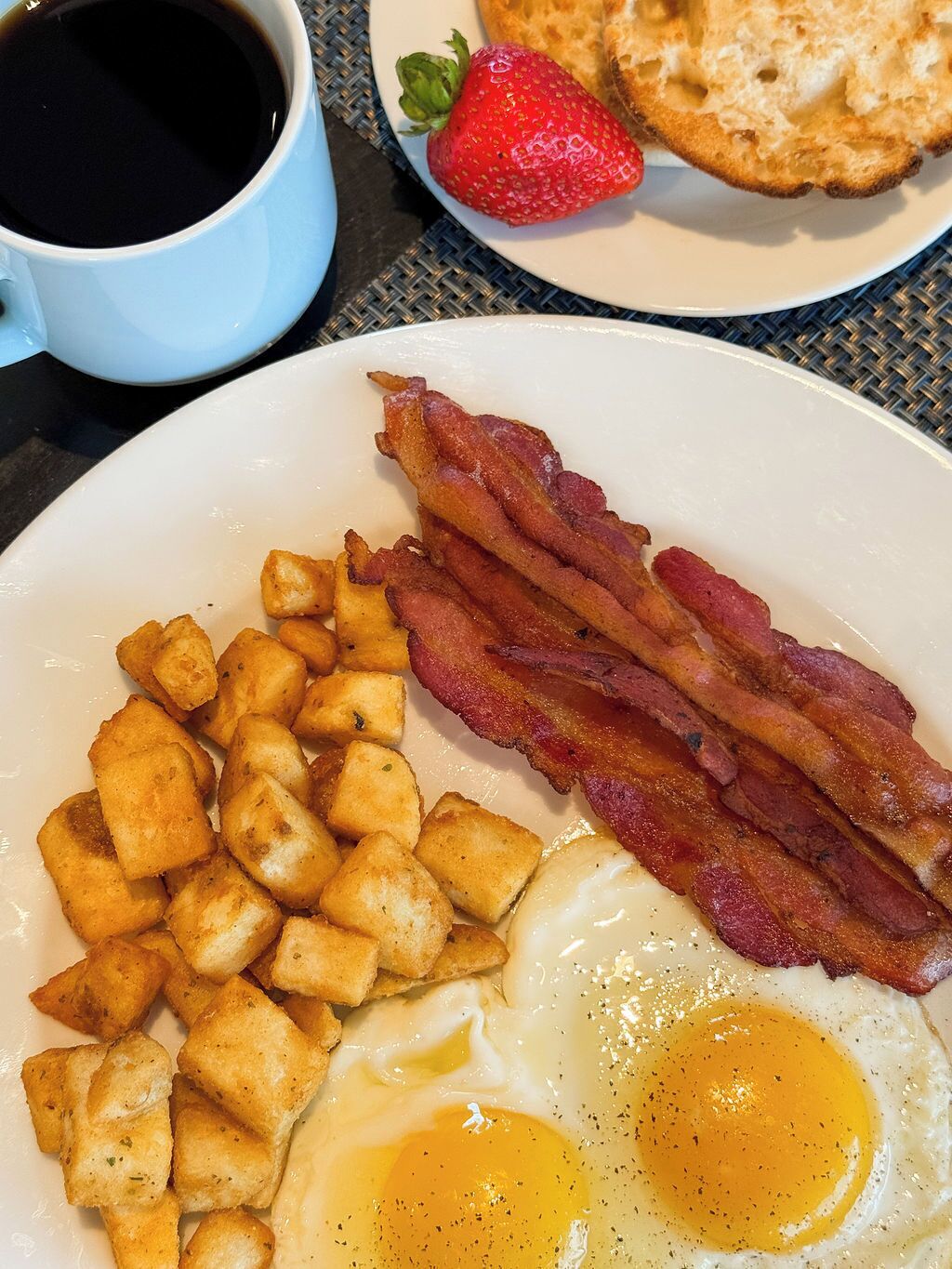 A breakfast plate with fried eggs, bacon, and hash browns.