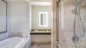 A bathroom with a bathtub, a shower, a vanity with a mirror, and a light fixture above the mirror.