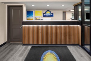 A reception area with a wooden reception desk, a 'Days Inn' sign, and a 'Hello Sunshine' sign.