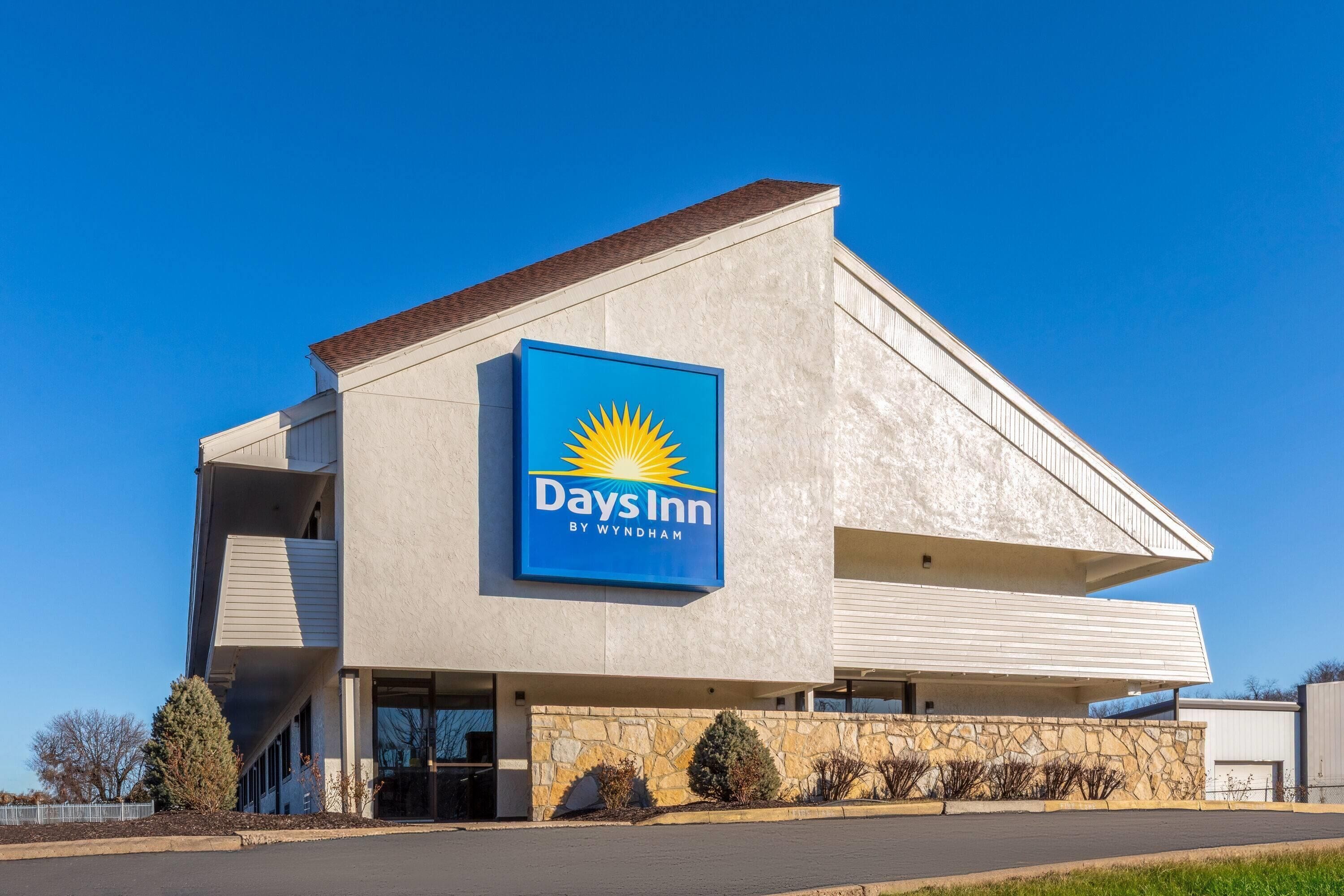 Edificio de Days Inn by Wyndham con un letrero llamativo, techo plano y fachada de piedra.