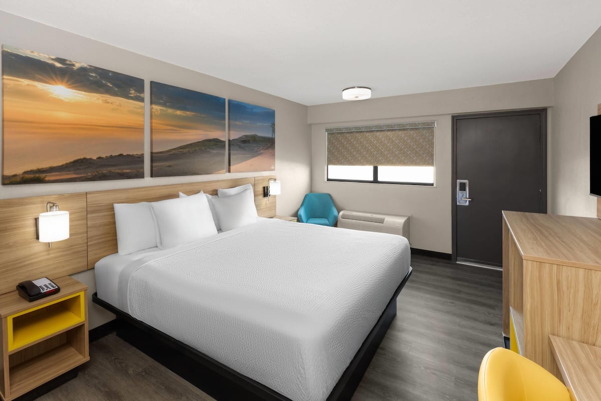 A hotel room with a large bed, a desk, a chair, and a TV.