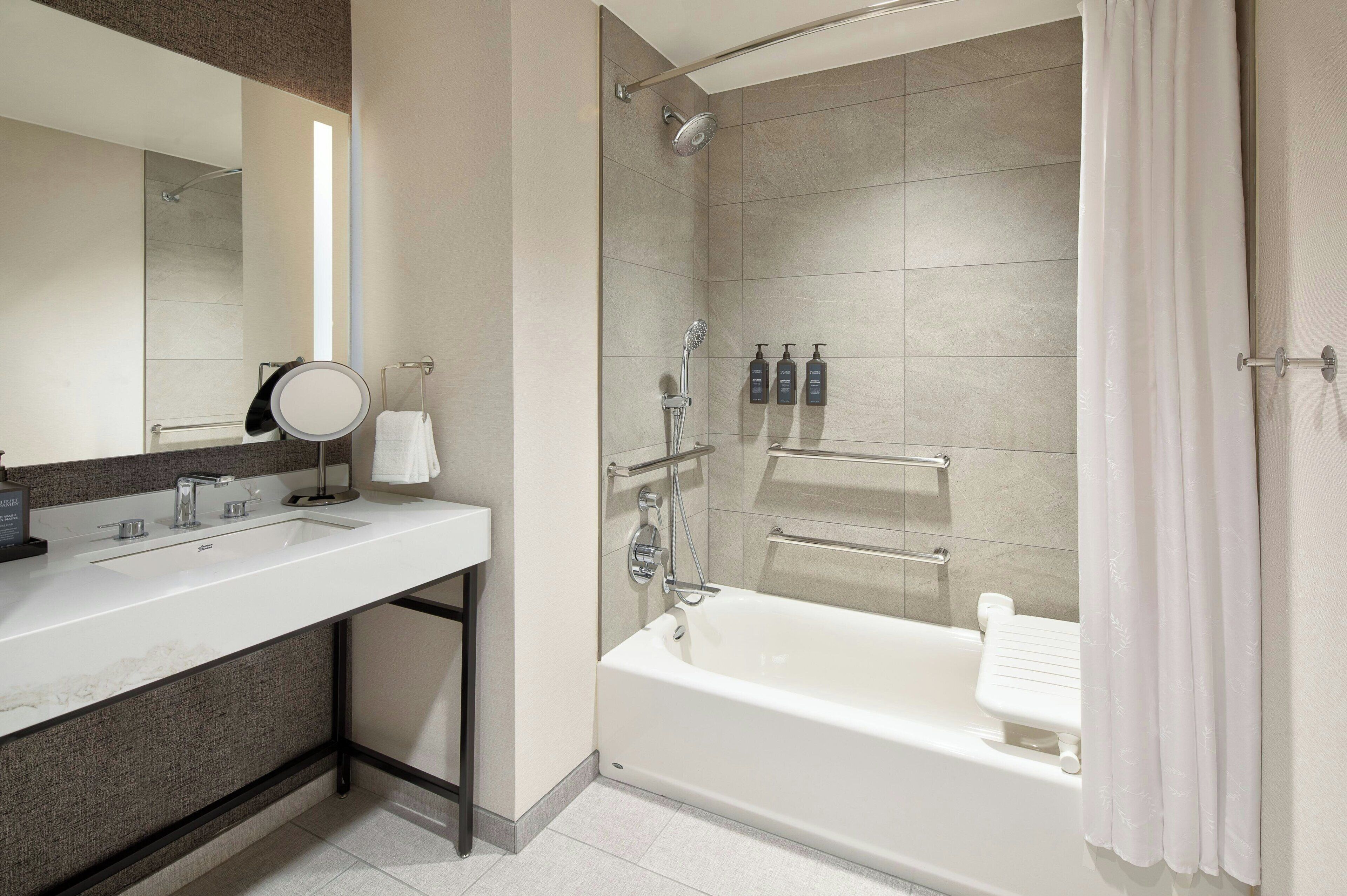 A modern bathroom with a large bathtub, a separate shower area, and a vanity with a sink and mirror.