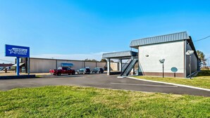 A commercial building with a parking lot, a sign for 'Americas Best Value Inn by Sonesta', and a satellite dish on the roof. - Americas Best Value Inn Indianola (Indianola)