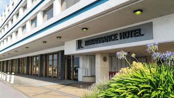 The exterior of Renaissance Hotel with a modern facade, large windows, and a well-maintained garden area.