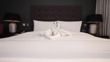 Habitación de hotel con una cama bien hecha, dos lámparas de noche y un cabecero oscuro.