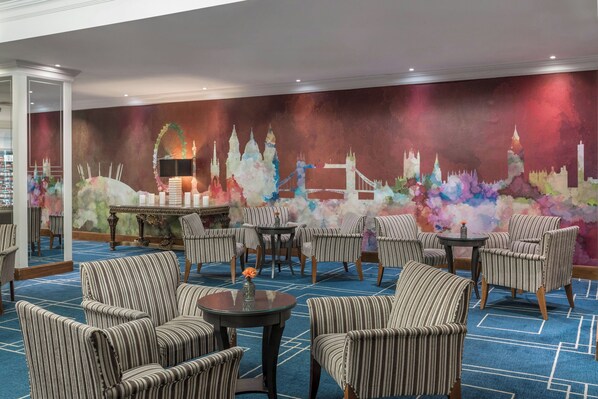 Experience the vibrant cityscape in our hotel lobby, featuring a striking mural and stylish seating areas.
