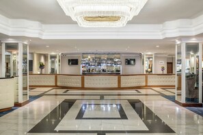 Experience the grandeur of our lobby, featuring a stunning chandelier, geometric tile floor, and elegant artwork.