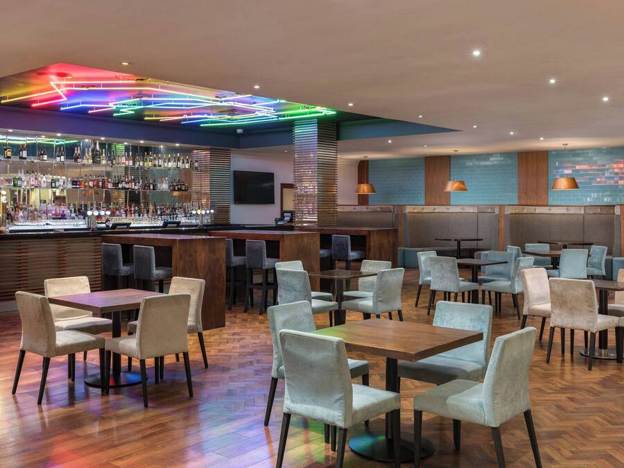 Un bar moderno con diversas opciones de asiento, incluyendo mesas y sillas, y una barra bien surtida.